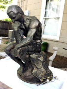 Rodin's The Thinker, polished bronze, with an alternate head/face.